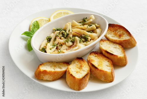 fried seafood dressed with finely chopped green herbs and garlic, olive oil, and lemon juice served with fried baguette, slices of lemon decorated with basil 