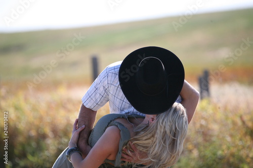 Cowboy kissing woman in field