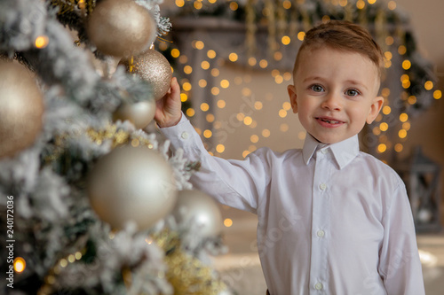 little boy decorates a Christmas tree for Christmas