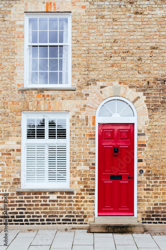 Typical British townhouse facade with red door and brick wall in St Ives, Cambridgeshire, England