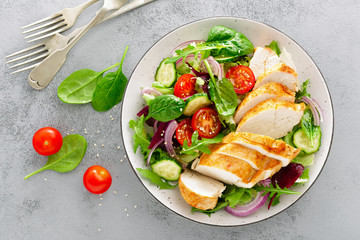 Grilled chicken breast, fillet and fresh vegetable salad of lettuce, arugula, spinach, cucumber and tomato. Healthy lunch menu. Diet food. Top view
