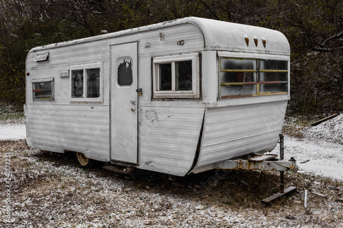 Vintage mobile home trailer at an angle on snowy ground