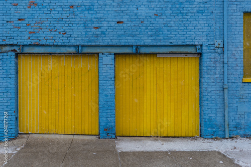 Fototapeta Naklejka Na Ścianę i Meble -  Blue bricks and yellow doors of old building with small patches of snow