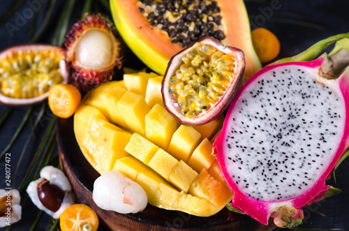 Mix of ripe tropical fruits with mango, dragon fruit, passion fruit, kumquat, papaya and lychee. Vegetarian raw food. Fruit cut. Close-up.