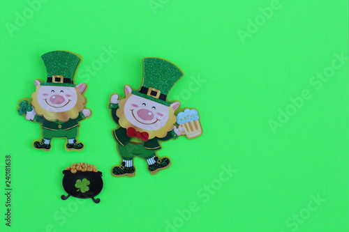 two leprechauns one dancing holding a beer laying flat next to a pot of gold on a green background with writing space