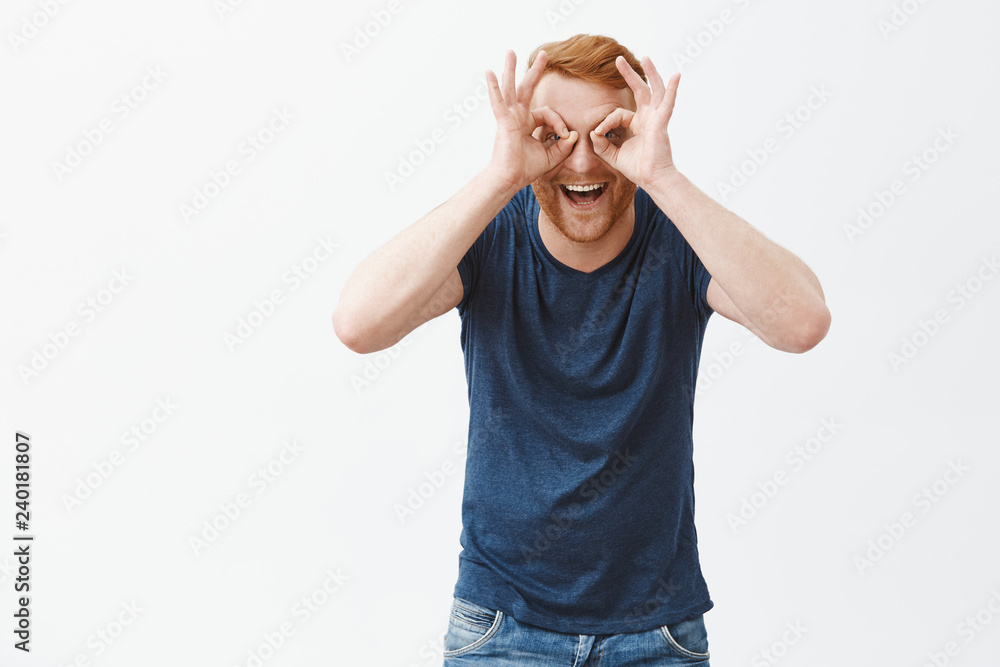 Man is large child. Joyful and playful emotive redhead guy with bristle, showing zero or okay gesture over eyes as if looking trought binocular, smiling happily and gazing at camera, having fun Man is large child. Joyful and playful emotive redhead guy with bristle, showing zero or okay gesture over eyes as if looking trought binocular, smiling happily and gazing at camera, having fun