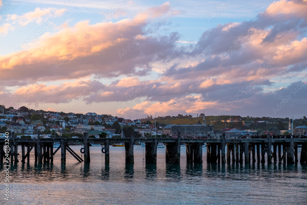 Obraz premium Beautiful sunset at the dock. Blue sky and Ocean with town view. Omaru, New Zealand.