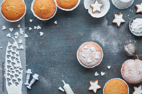 Top view of the table with sugar-sprinkled muffins, fondant icing and Christmas star cookies on blue wood