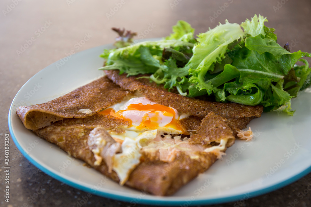 Filled with smoked ham, smoked salmon, grated cheese, sunny side up egg served with a green salad Filled with smoked ham, smoked salmon, grated cheese, sunny side up egg served with a green salad