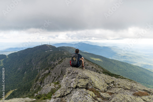a hiker enjoys the unparalled views atop a high mountain range in Vermont