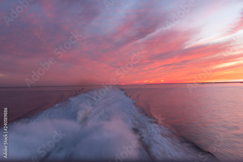 wake of a power boat with a sunset in the back photo