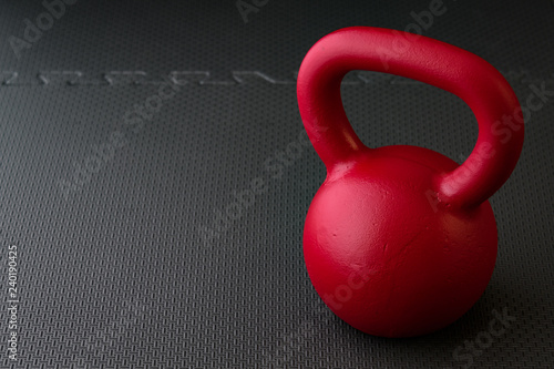 Fototapeta Naklejka Na Ścianę i Meble -  Red kettlebell on a black gym floor, simple commitment to fitness