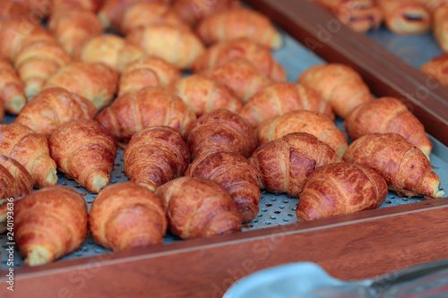 A lot of ruddy croissants on the buffet. A cropped shot, close-up, horizontal, side view. The concept of food and service.
