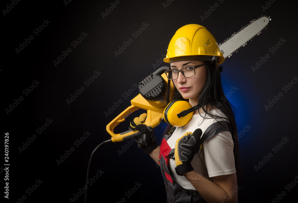 brunette girl in special clothes and a worker in a helmet posing on a black background with a working tool brunette girl in special clothes and a worker in a helmet posing on a black background with a working tool