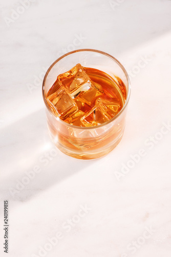 glass of whiskey or tea with ice on marble background vertical