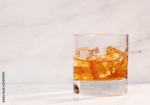 glass of whiskey or tea with ice on marble background horizontal side view
