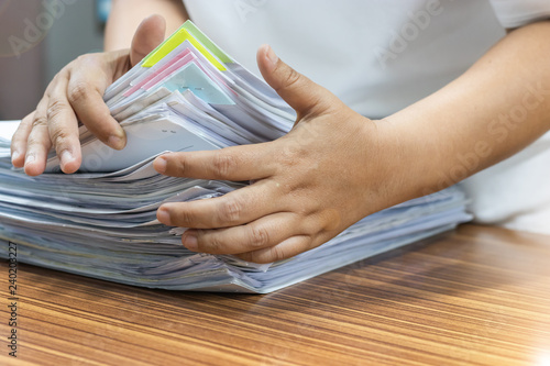 Teacher is searching for homework assignment documents of student on the teacher's desk. Paperwork pile print document organized put on the table.