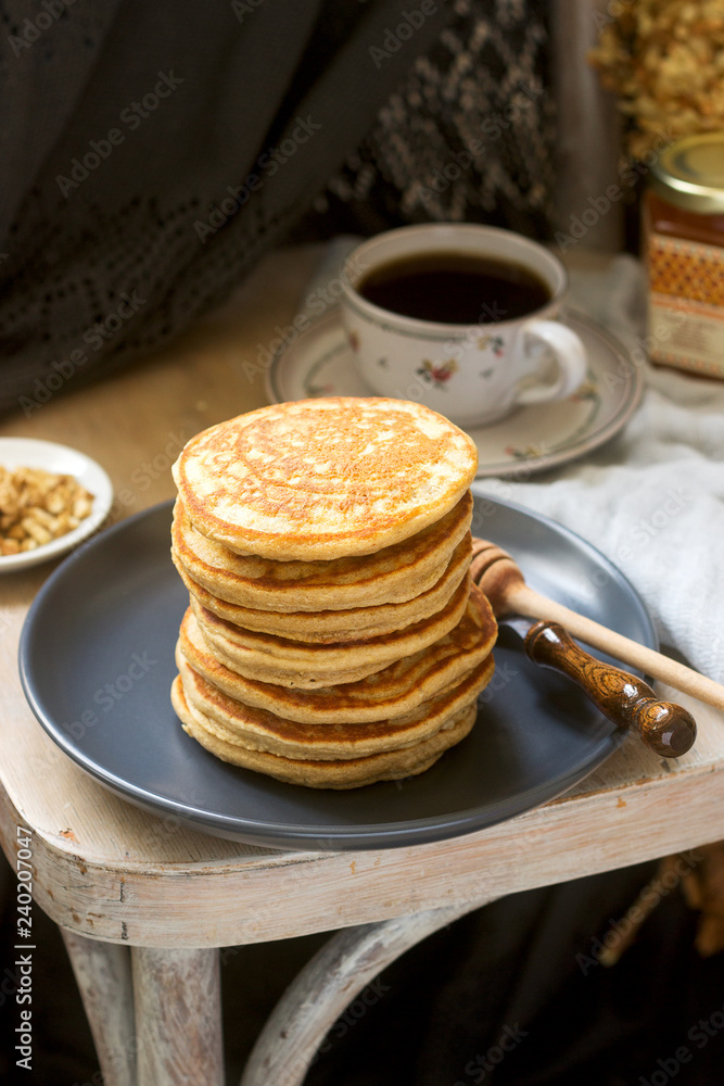 Pancakes with banana, nuts and honey, served with tea. Rustic style.
