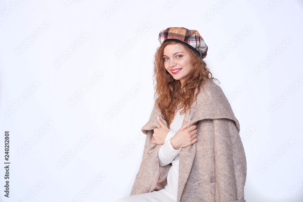 Beautiful girl dressed in french style on a white background. red hair woman is wrapped in a coat, winter clothes. Smiling lady wearing warm clothes, winter portrait Beautiful girl dressed in french style on a white background. red hair woman is wrapped in a coat, winter clothes. Smiling lady wearing warm clothes, winter portrait