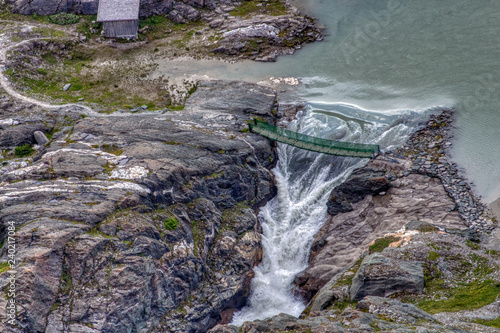 Obraz na płótnie Brücke über Wasserfall an Bergsee mit Felsen und Steinen w salonie