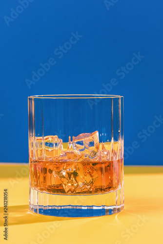 whiskey glass on blue and yellow closeup 