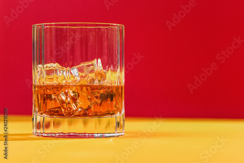 glass of whiskey and ice on red background horizontal 
