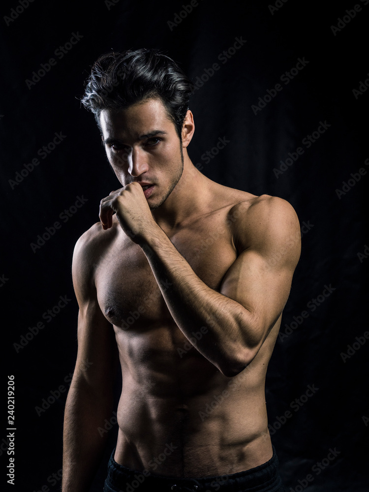 Handsome muscular shirtless young man standing confident, front view, looking at camera