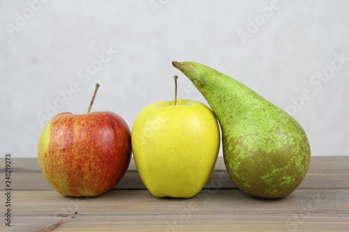 Owocowa dekoracja - czerwone i żółte jabłko z zieloną gruszką na jasnym tle