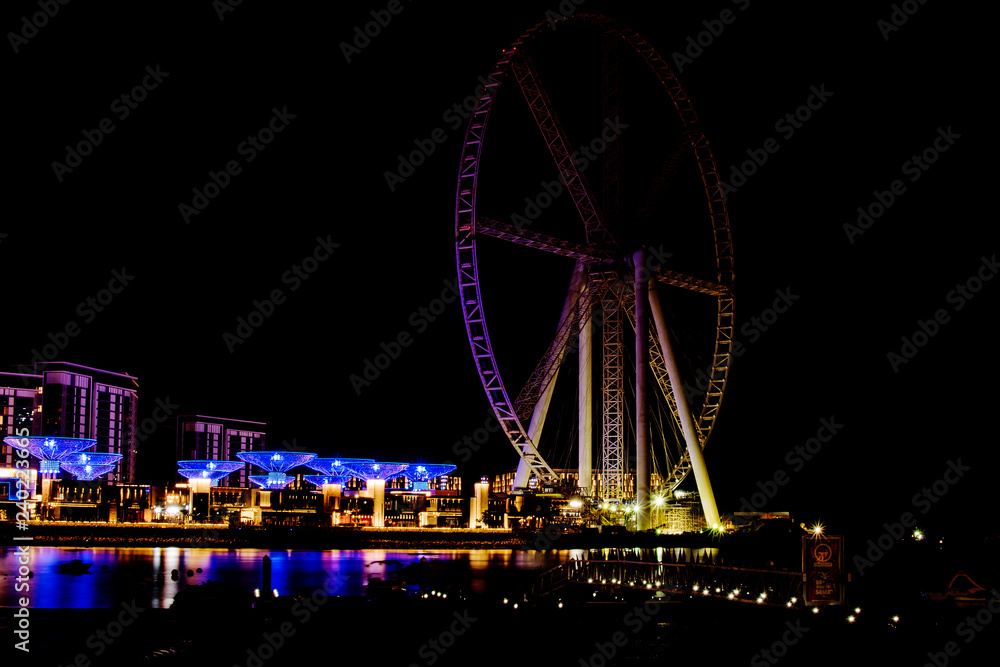 Dubai, UAE - November 19, 2018: Jumeirah Beach Residence JBR and the Dubai Ferris Wheel with night illumination.
