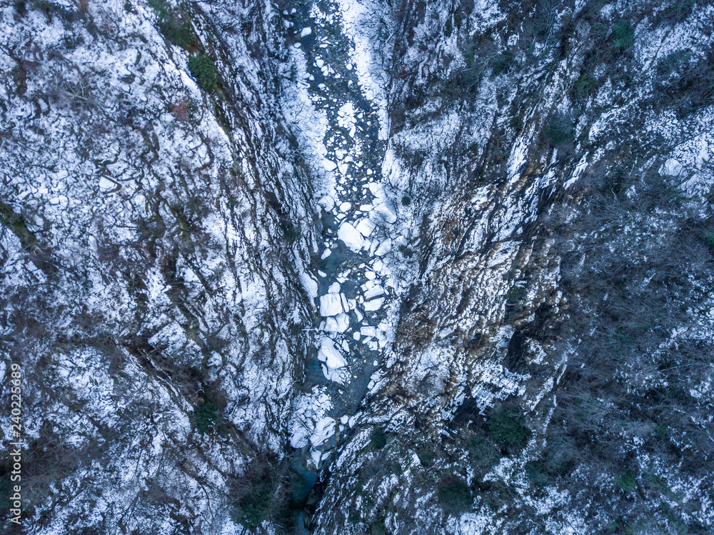 Aerial view of snow covered river in deep valley in remote mountains in Switzerland Aerial view of snow covered river in deep valley in remote mountains in Switzerland