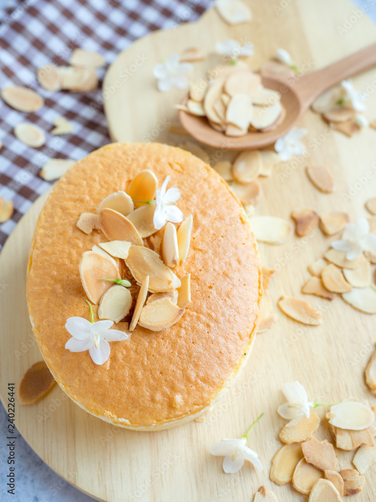 One piece of mini cheese cake with almond on top on wood tray for menu or bakery business. One piece of mini cheese cake with almond on top on wood tray for menu or bakery business.