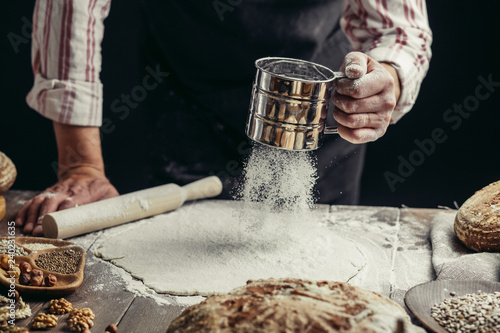 Flour being passed three times through a sieve before professional Chef put it on a piece of dough for delicate delicious pizza, close up
