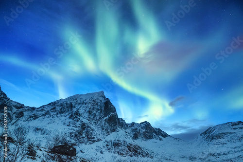 Aurora borealis on the Lofoten islands, Norway. Green northern lights above mountains. Night sky with polar lights. Night winter landscape with aurora. Natural background in the Norway