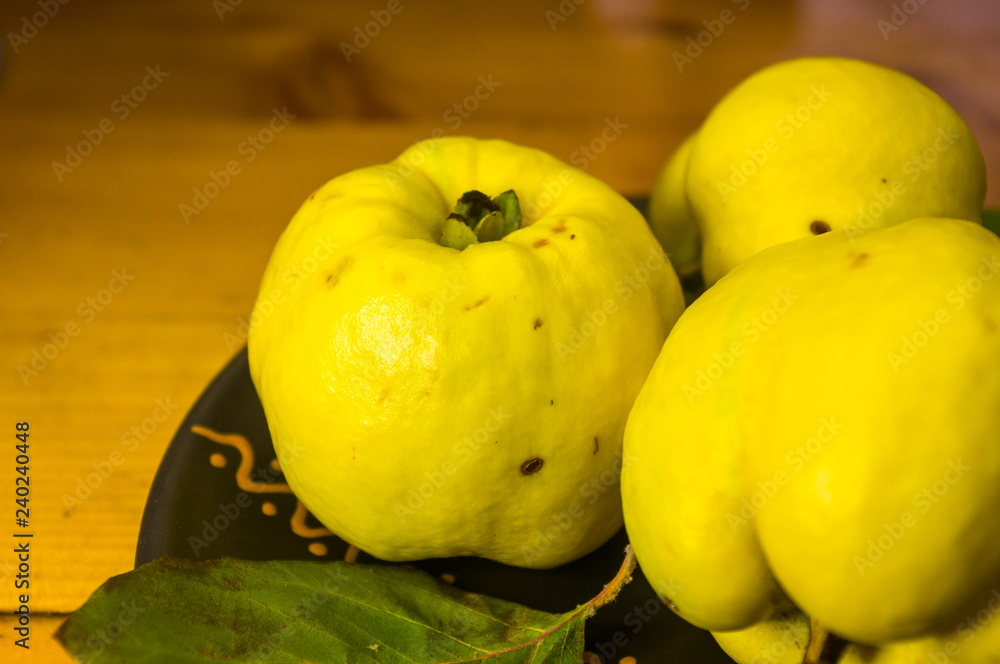 large yellow quince fruits on a ceramic plate, with anise, cinnamon, and walnuts