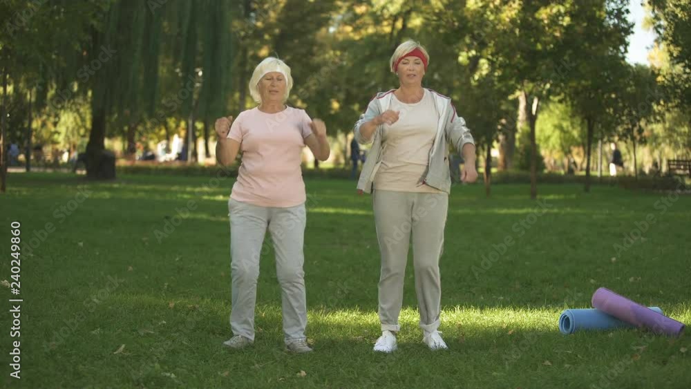 Mother and her daughter doing exercises in park, warming up before workout Mother and her daughter doing exercises in park, warming up before workout