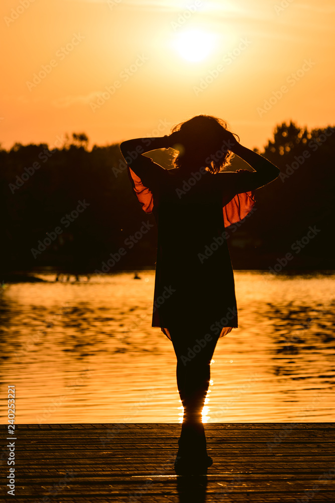 silhouette of young woman on the lake at sunset