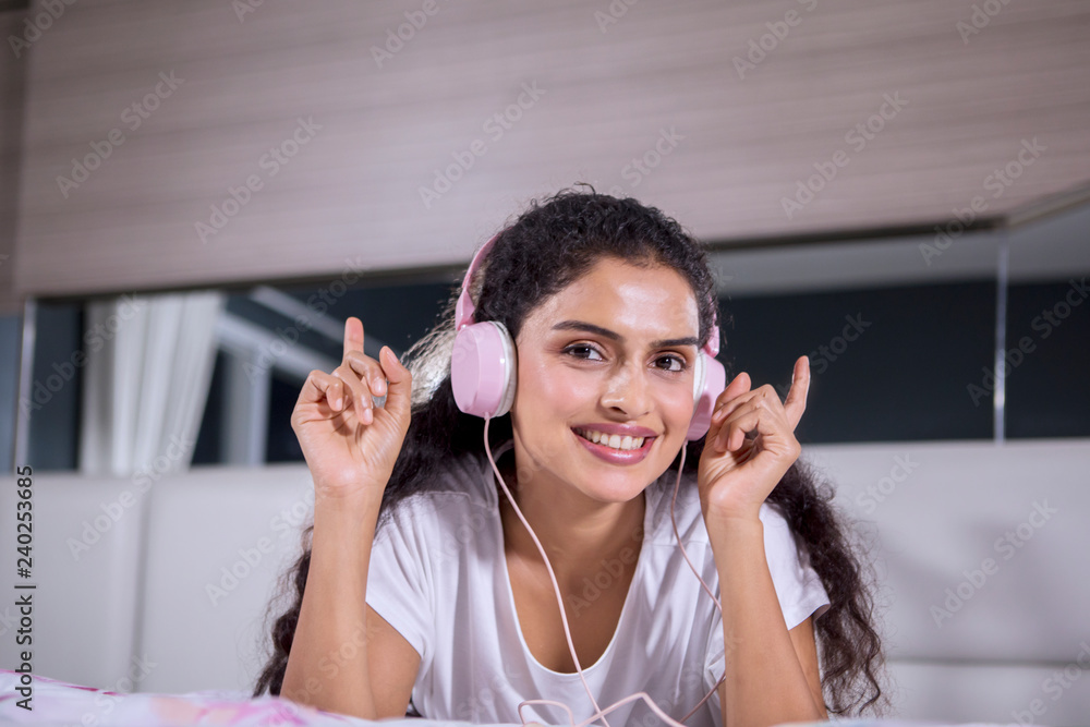 Happy woman enjoys music on the bed