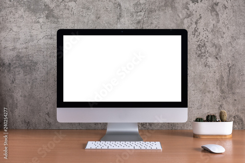 Blank screen of all in one computer with cactus vase on raw concrete background