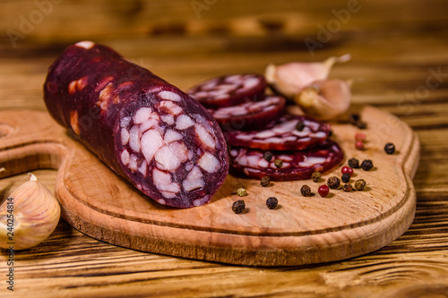 Cutting board with sliced salami sausage and garlic on a wooden table