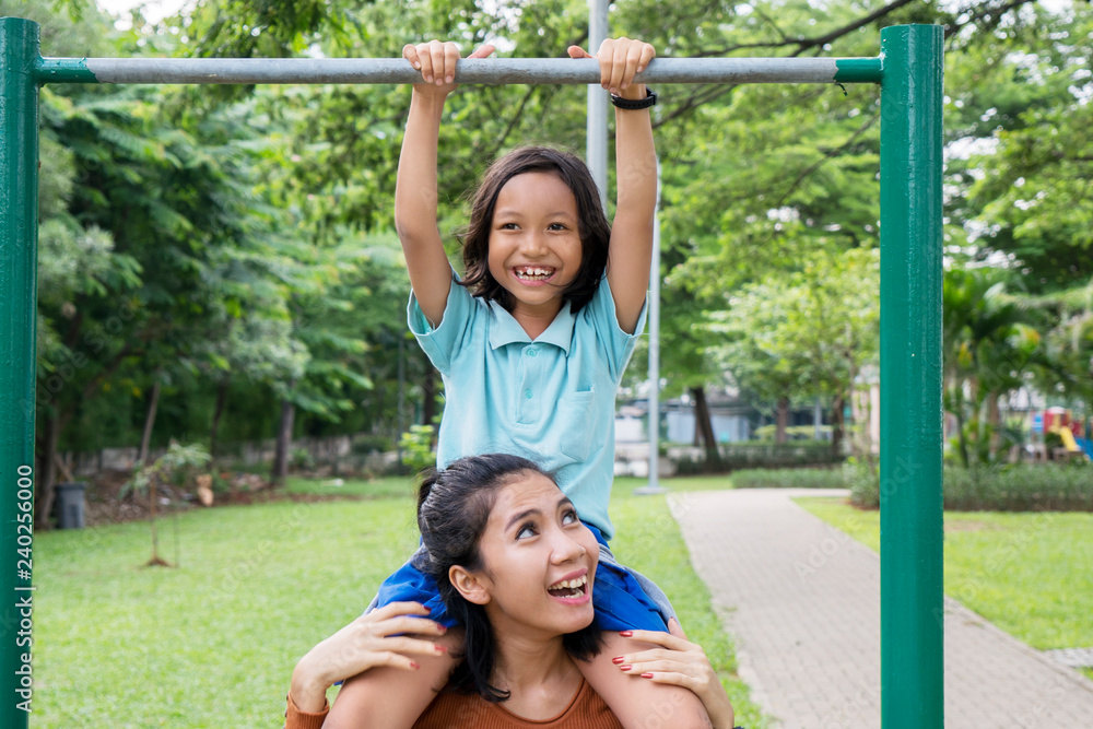 Fototapeta premium Woman helps her daughter to do pull up exercises