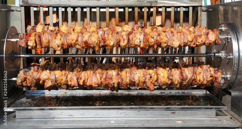 big skewers of chicken and pork meat while they cook very slowly