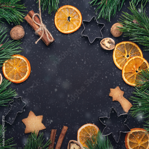 Homemade fresh cookies Fir branches Dried slices of orange Cookie cutters Christmas concept Nuts Cinnamon Top view Copy space Snow effect