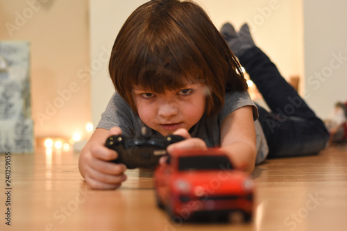 Boy playing with a red car on remote control. Child play with a toy car