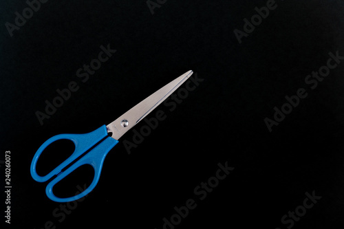 A pair of blue scissors on the left of a black background