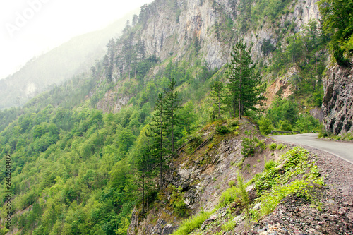 A winding road along a rocky canyon with vegetation.