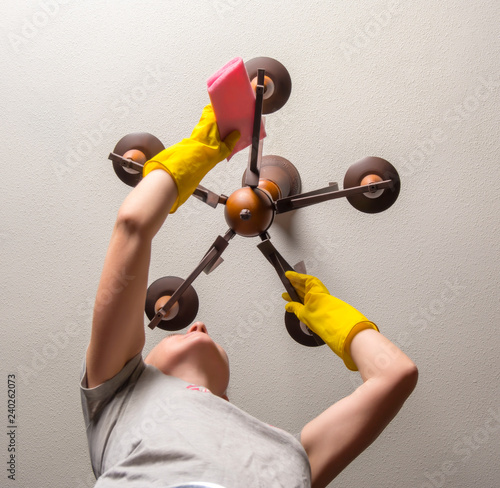 The maid does the housework and washes the chandelier. The concept of keeping the house clean. photo