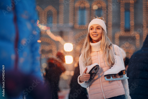 Young smiling woman with skates on the ice rink