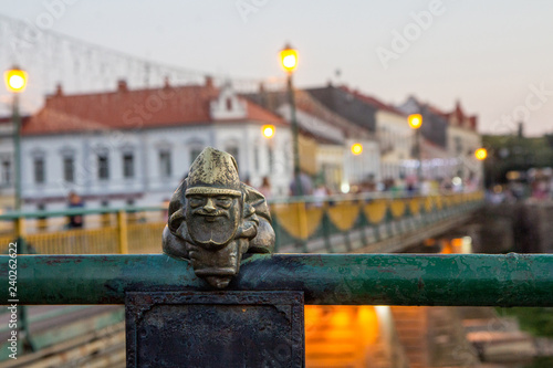 Uzhgorod, Ukraine, August 29, 2017: Mini sculpture of Mikolajczyk, the Santa's helper on the handrail of the bridge on the background of the evening city photo