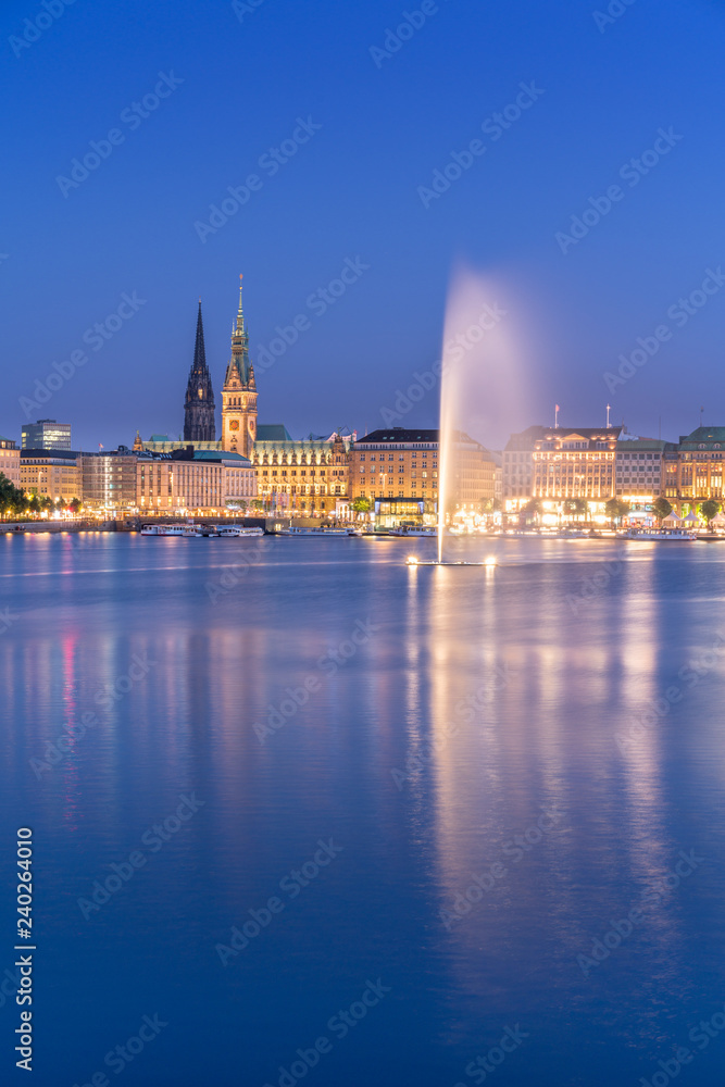 The Inner Alster Lake (German: Binnenalster) in Hamburg, Germany. View of the inner city at dusk with the fountain reflecting in the water.