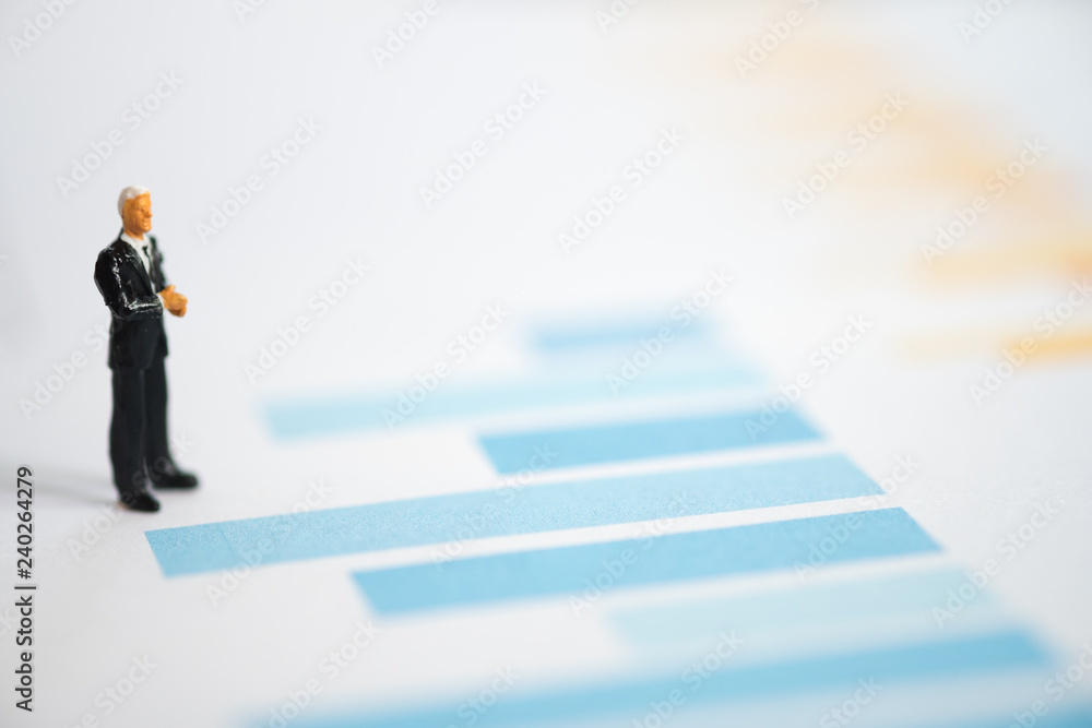 Miniature figures businessmen standing on a graph chart financial. Miniature figures businessmen standing on a graph chart financial.